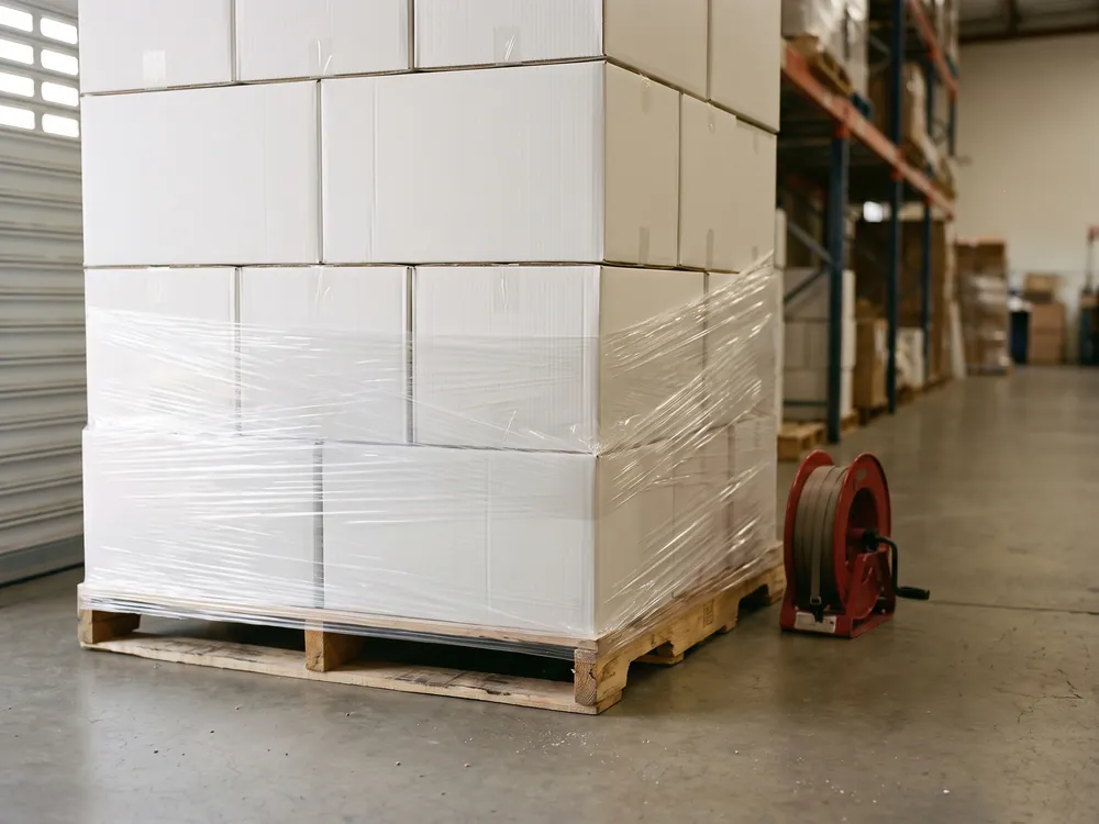 Tarima de cajas blancas siendo emplayada con película transparente en el área de empaque